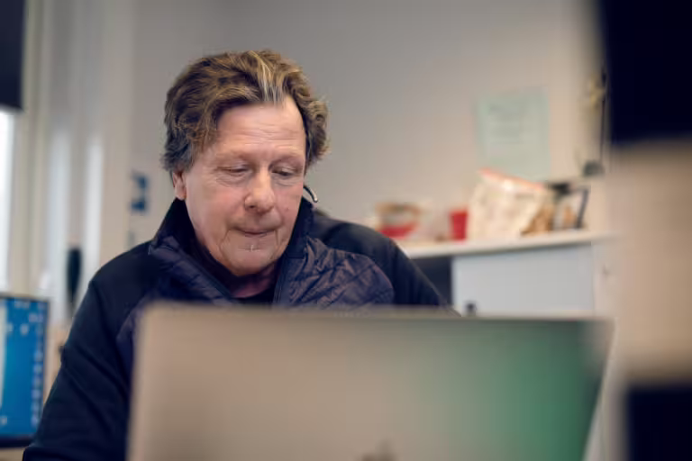 Mann i brakkebygning som jobber ved PC.