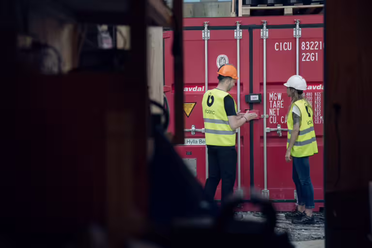 två byggarbetare vid container med containerlås.