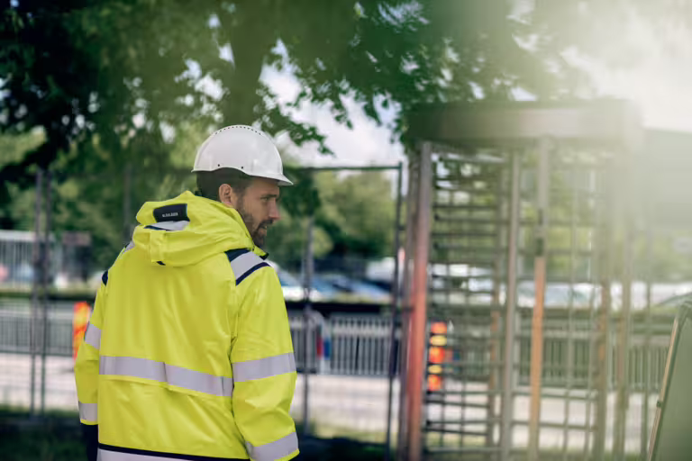 Byggarbetare vid inhägnad byggarbetsplats med grind för kontrollerad in- och utpassering