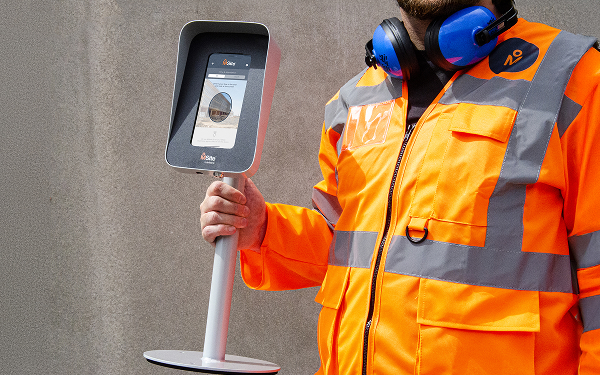 construction worker in an MSite jacket holding a face mini device